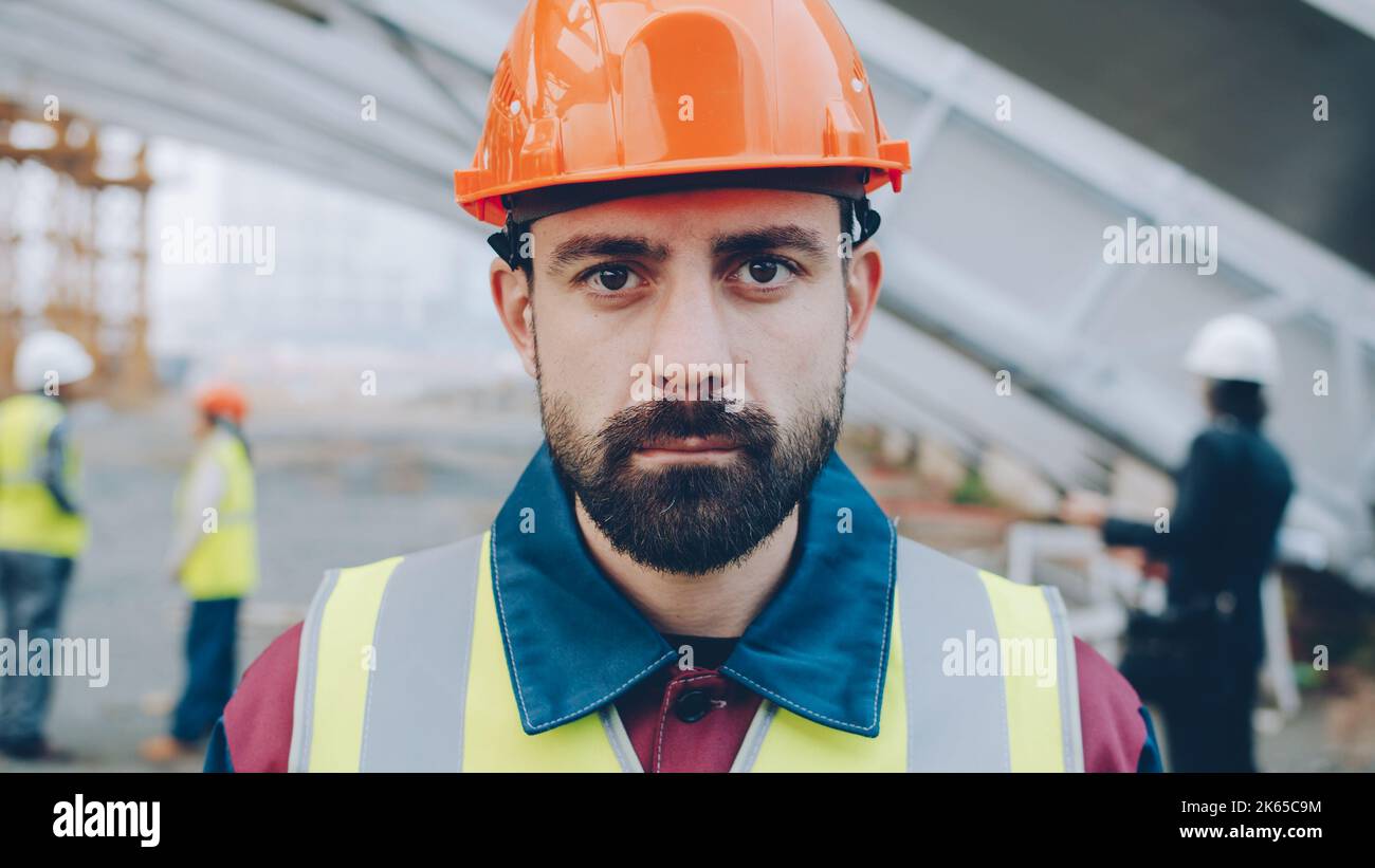 Closeupportrait of serious guy wearing safety helmet and west standing