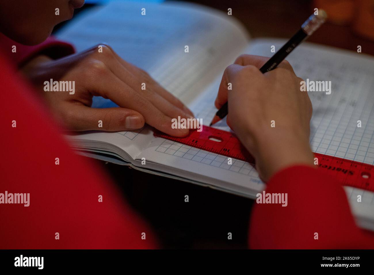 A young girl drawing with a pencil and a ruler practicing for her exams ...