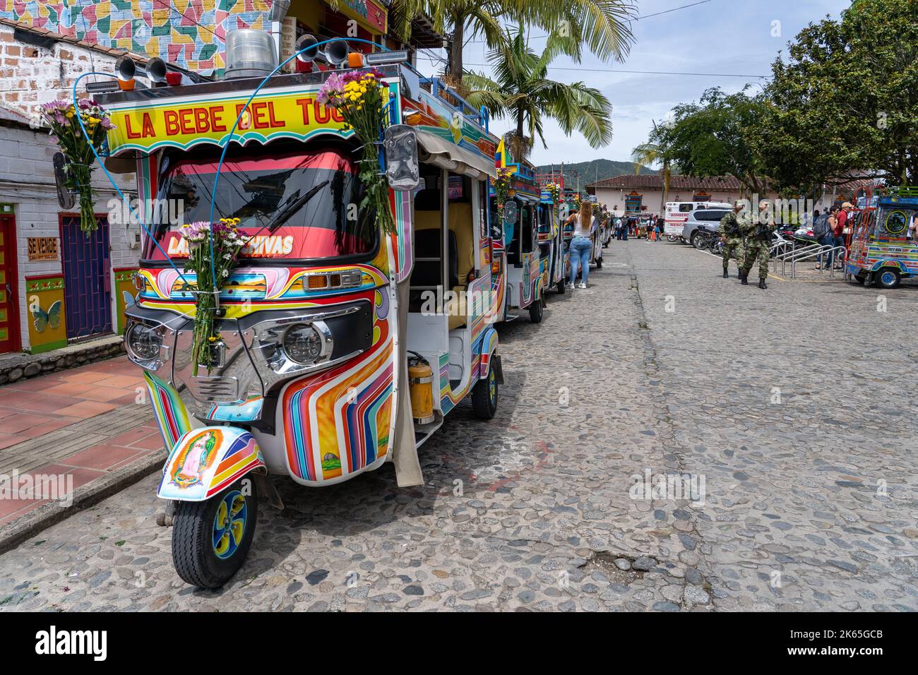 A colorful motorcycle taxi in the street with trees and people in the background, Guatape, Colombia Stock Photo