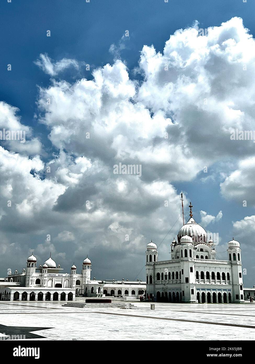 A vertical shot of Kartarpur Sahi with big white clouds above it in