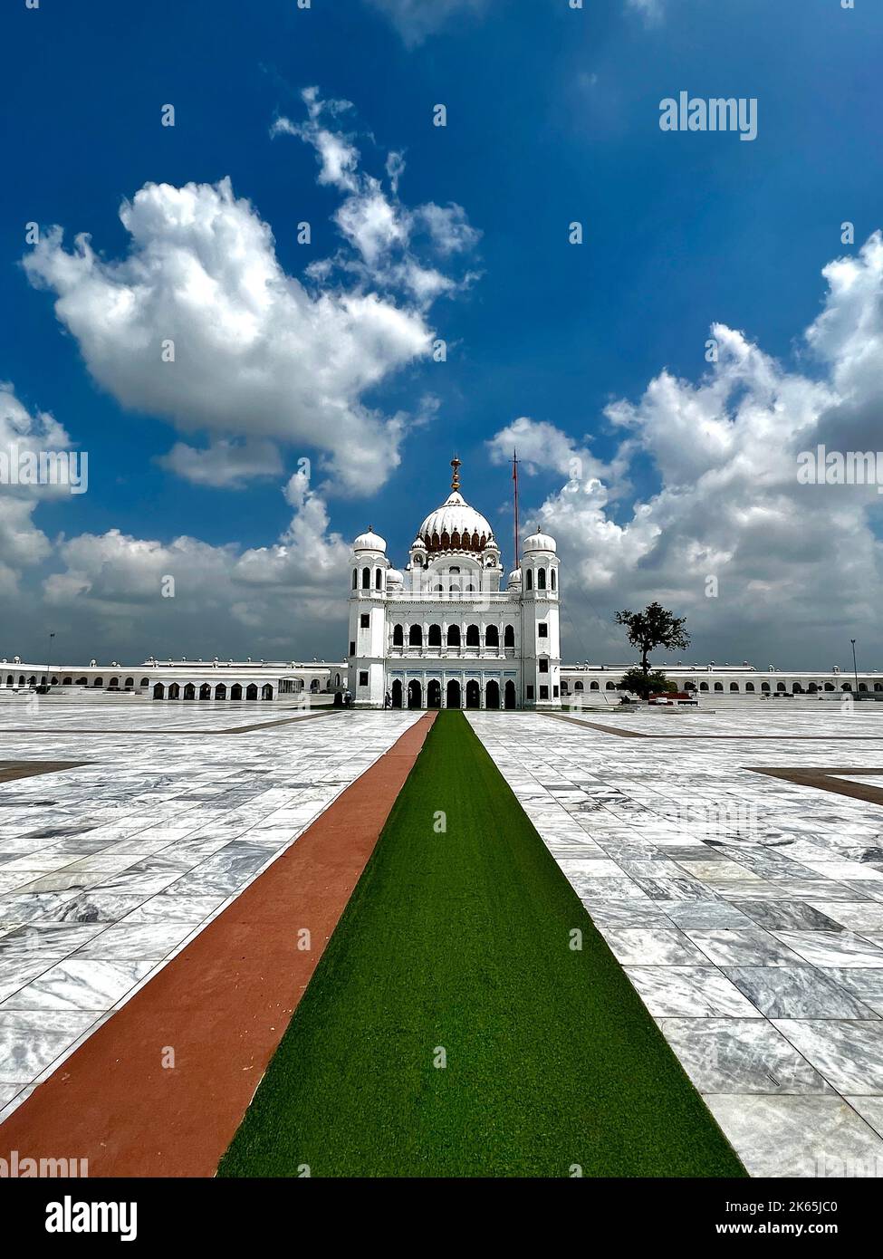 A vertical shot of Kartarpur Sahi with big white clouds above it in