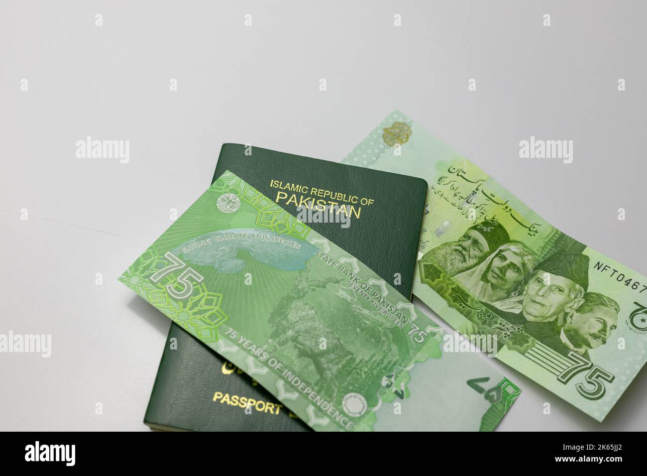 Pakistani new 75 rupees banknote with a Pakistan passport on white isolated background Stock Photo
