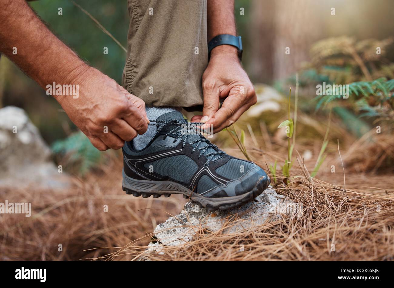 Lace up those hiking boots. a man tying his shoelaces while out hiking