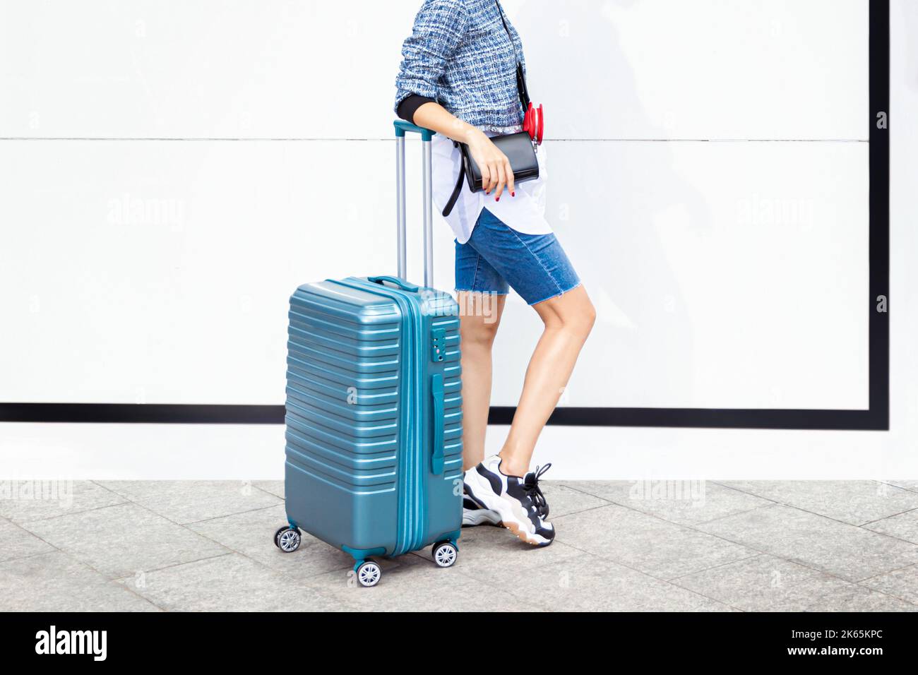 Female traveler walking with blue suitcase on white background Stock Photo