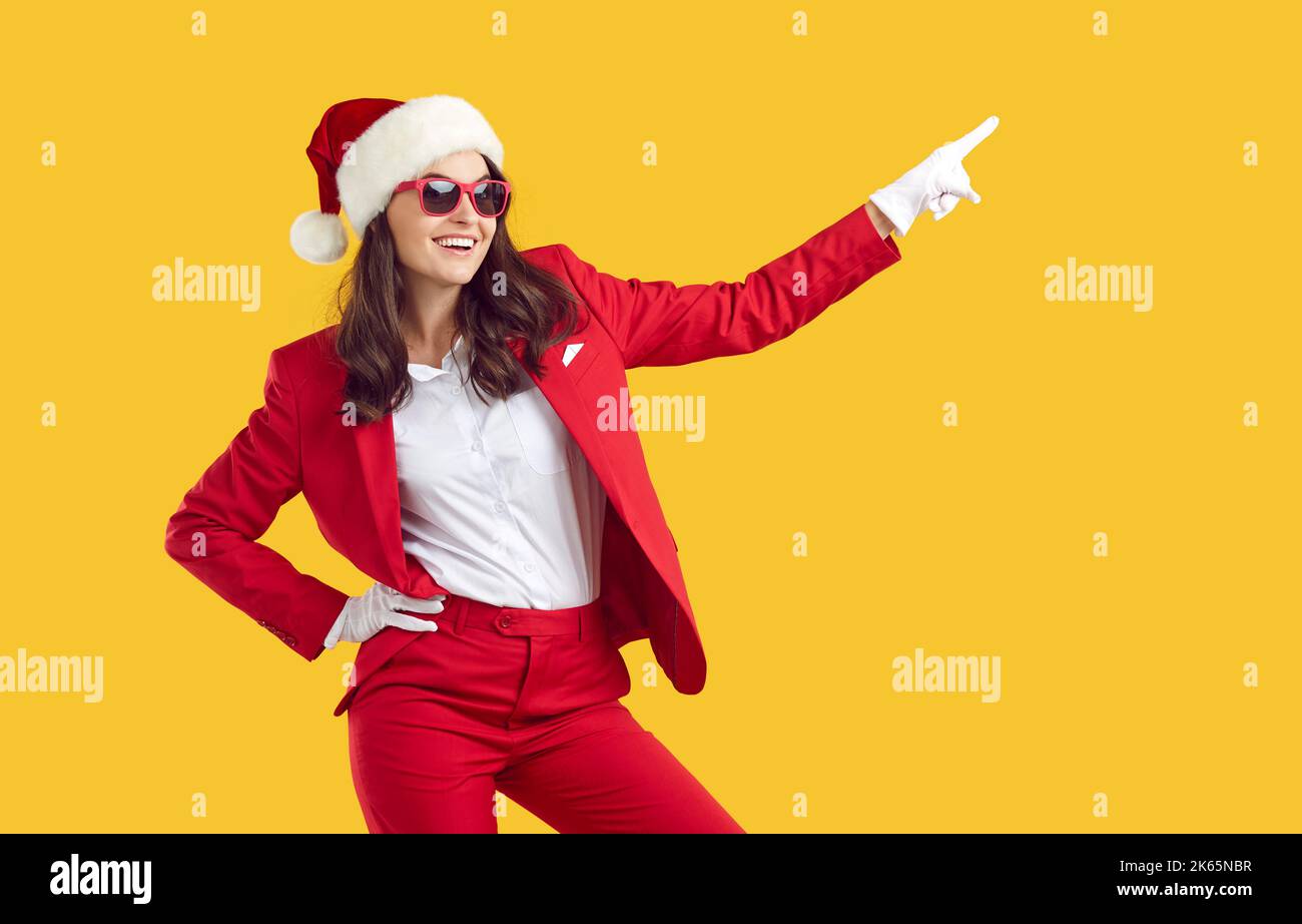 Happy beautiful woman in Christmas costume pointing to side on yellow background Stock Photo