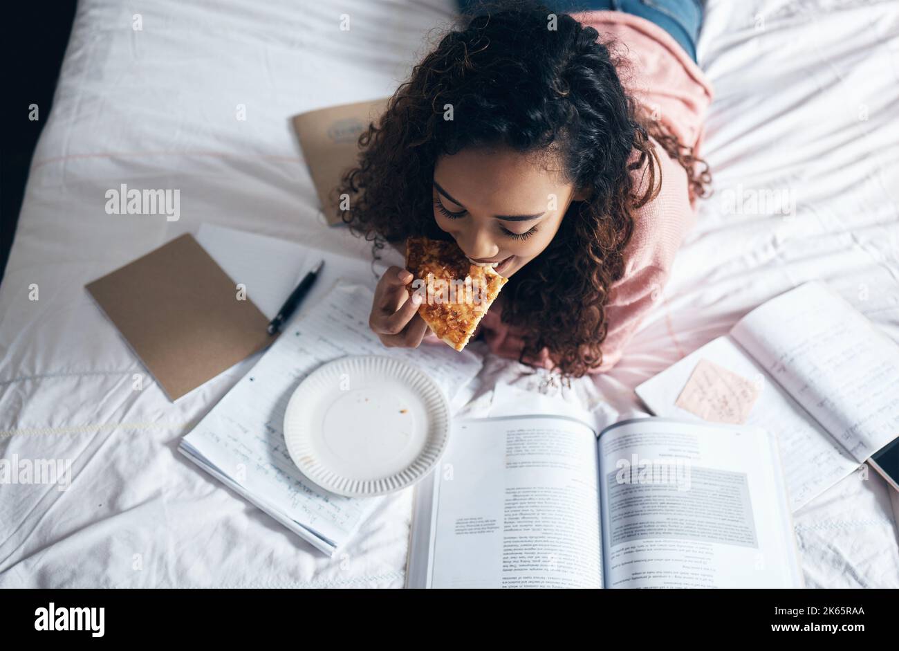 Bed, girl and student studying with pizza for lunch in her bedroom
