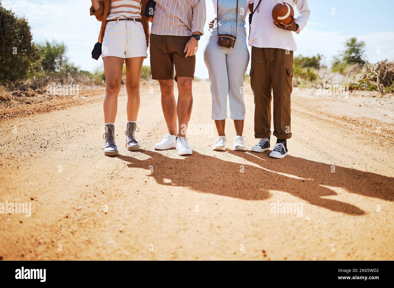 Shoes, shadow and friends on a sand road in the desert for summer