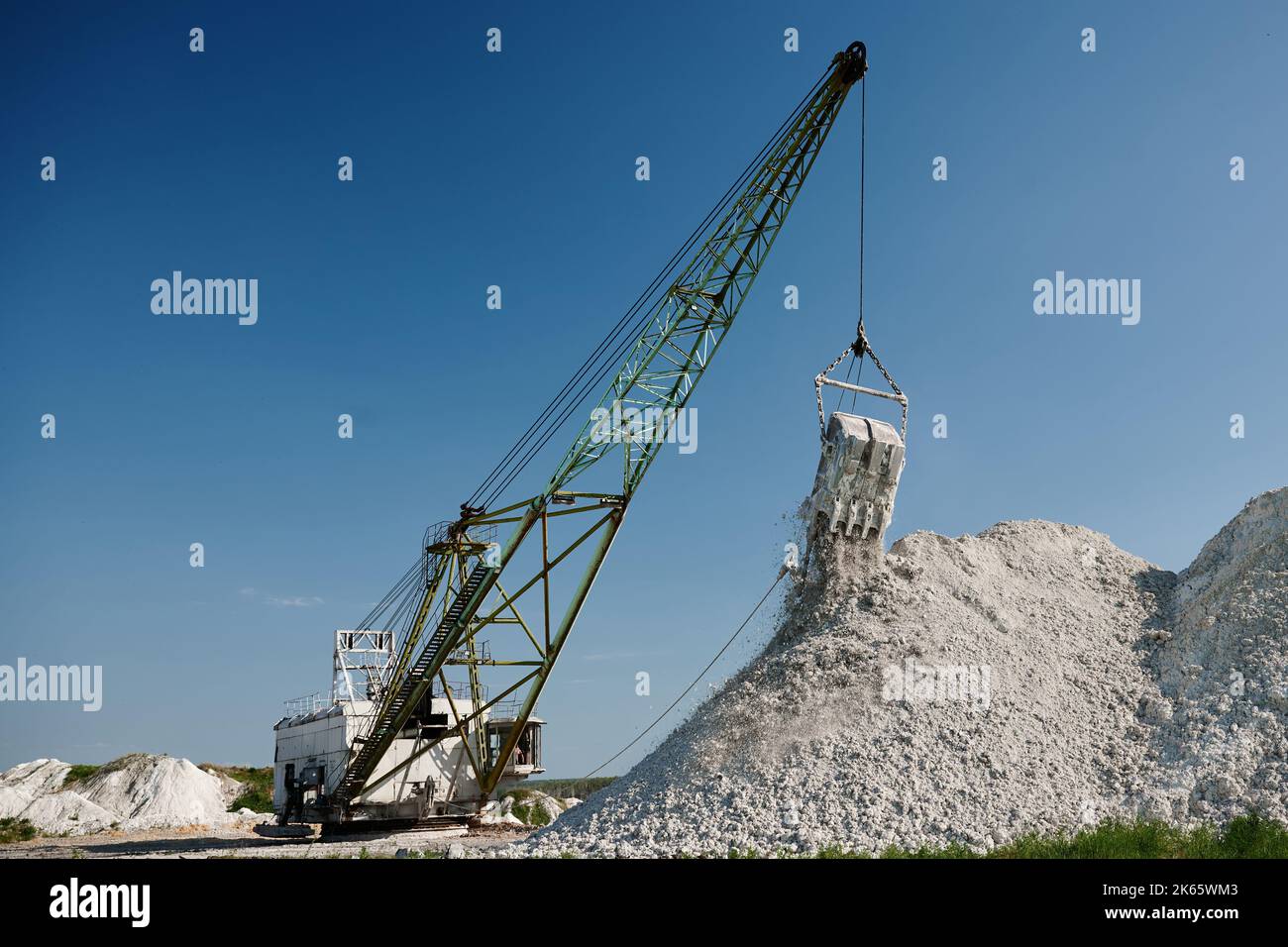 Dragline pours chalk out of bucket at pit against clear sky Stock Photo