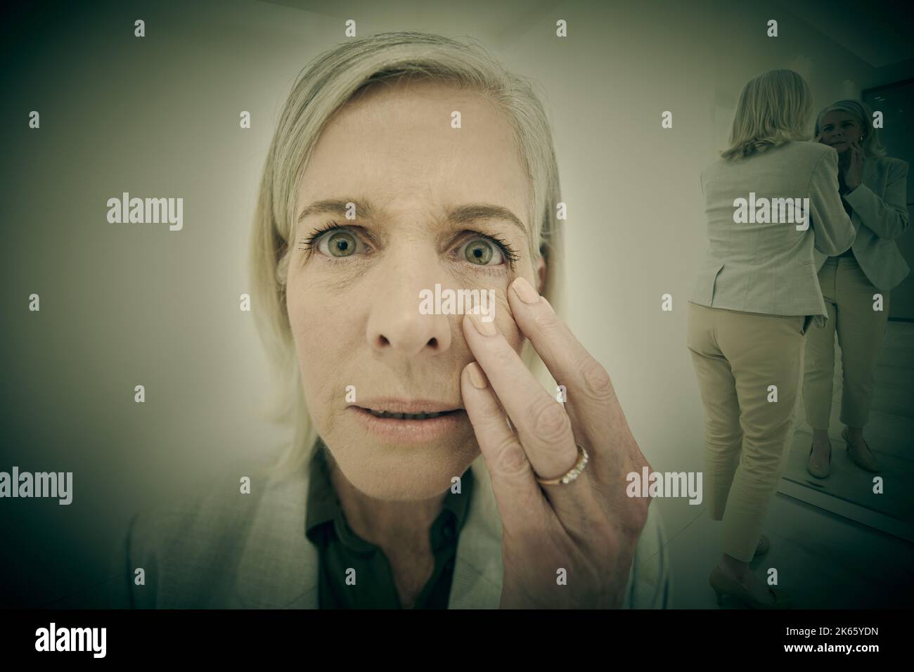 One Caucasian woman suffering mental illness in an asylum. A mature woman terrified after experiencing Alzheimers memory disease. Older woman becoming Stock Photo