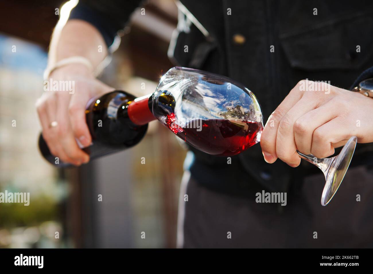 Man pouring wine into wineglass, male hand holding bottle Stock Photo