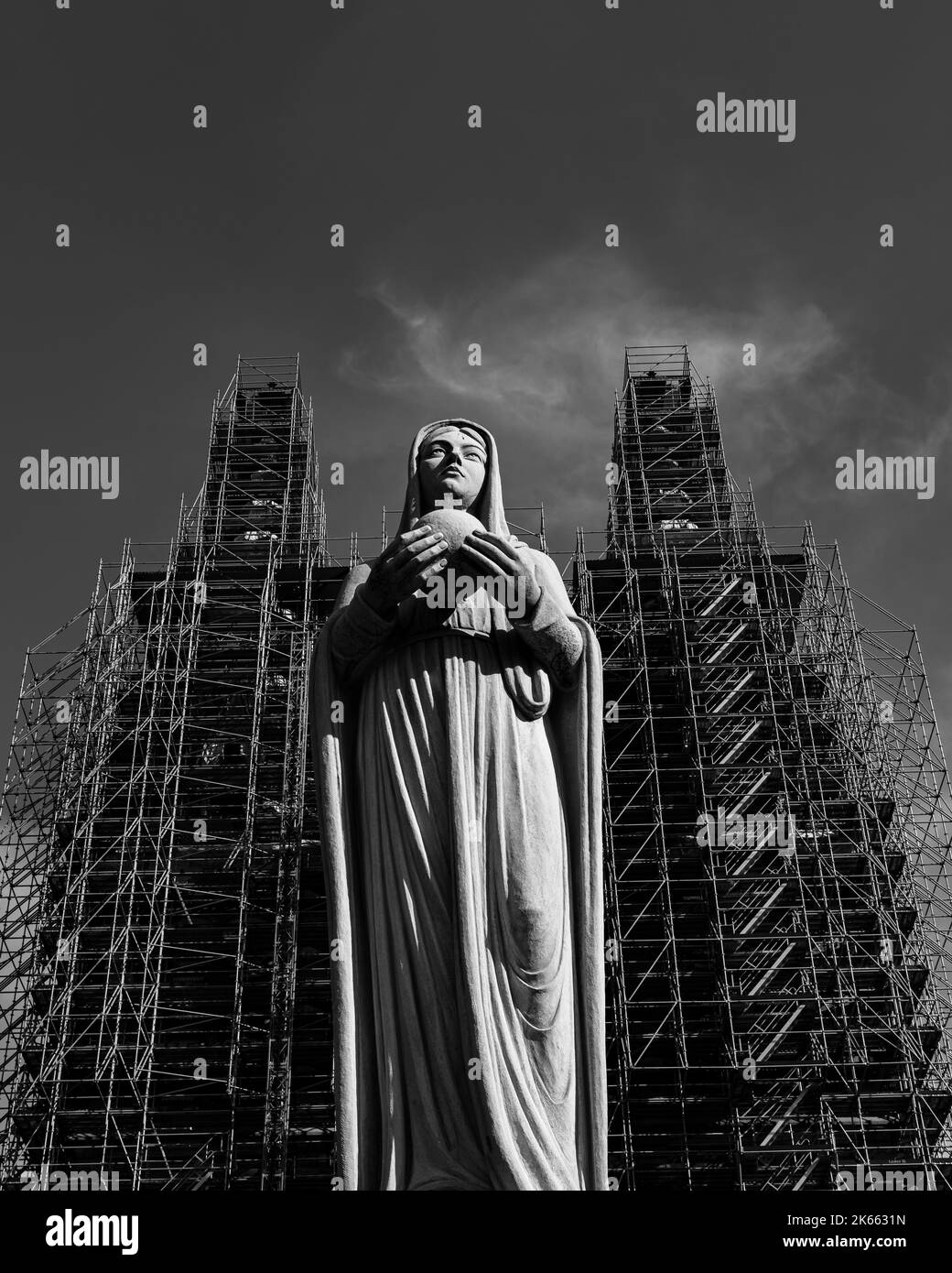 A grayscale lowangle shot of a praying Virgin Mary statue with a