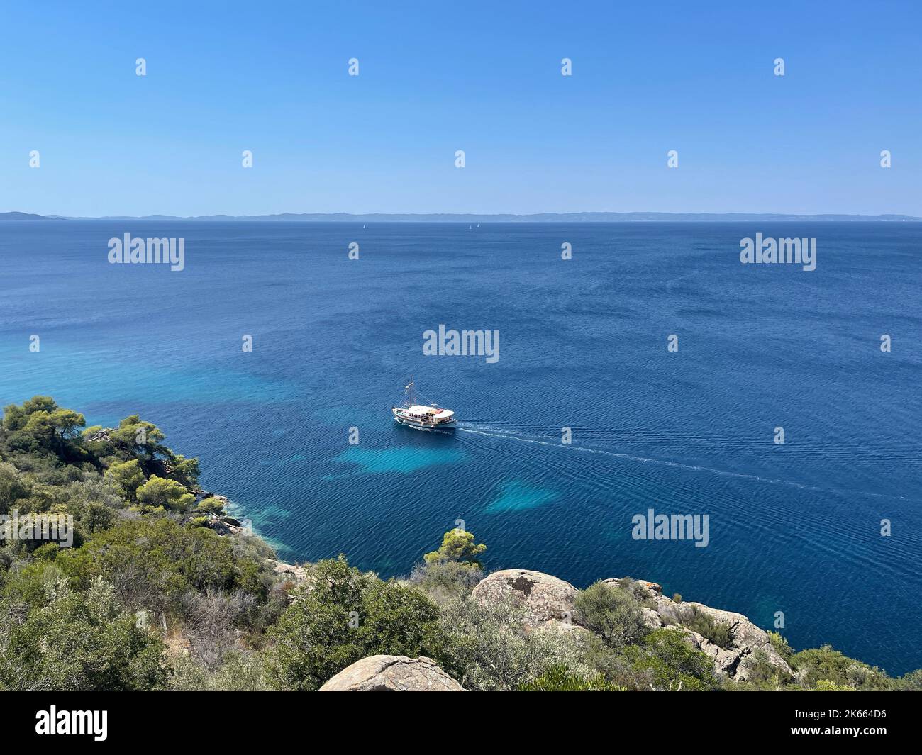 An aerial view of a boat sailing in the vast blue ocean in blue sky ...