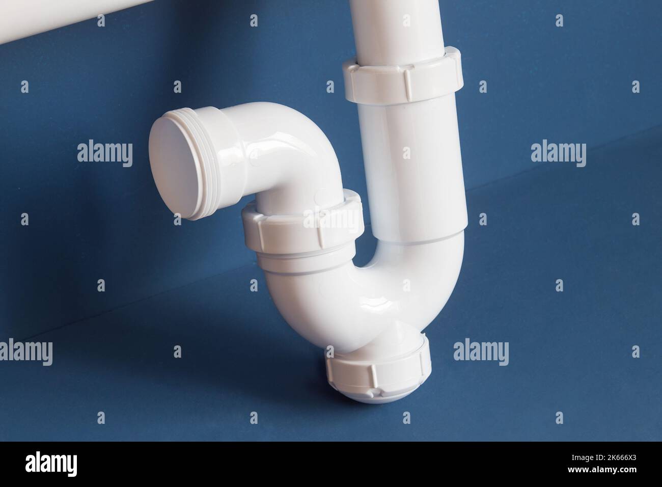 Detail of part of the siphon with a curved pipe with a drain cover on a blue studio background. Objects and maintenance. Stock Photo