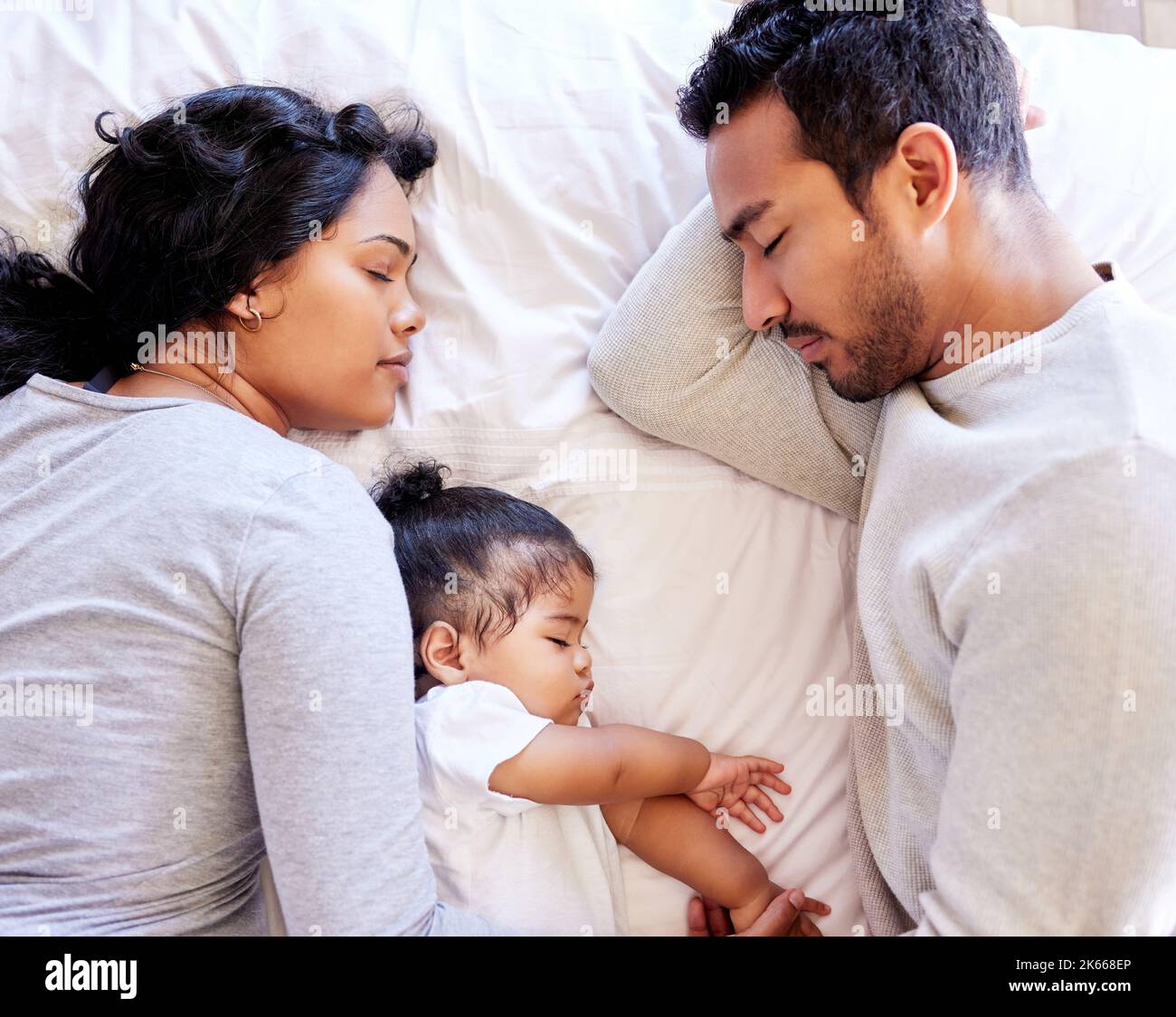 Young family sleeping together from above. Two parents sleeping with their baby girl. Little baby sleeping with her parents. Mother and father Stock Photo