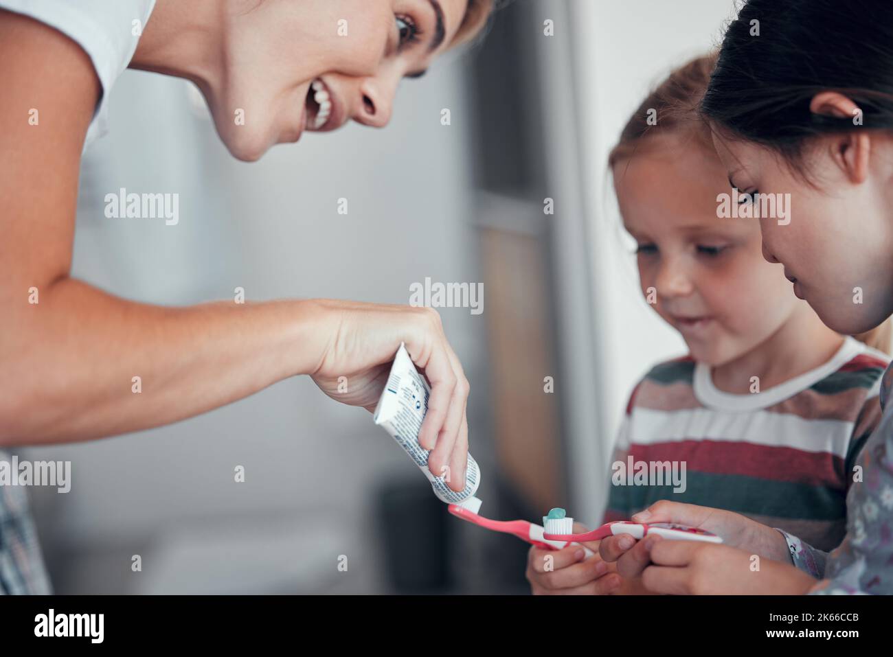 Habits Toothpaste Caucasian mom squeezing toothpaste from a tube onto toothbrushes of two ...