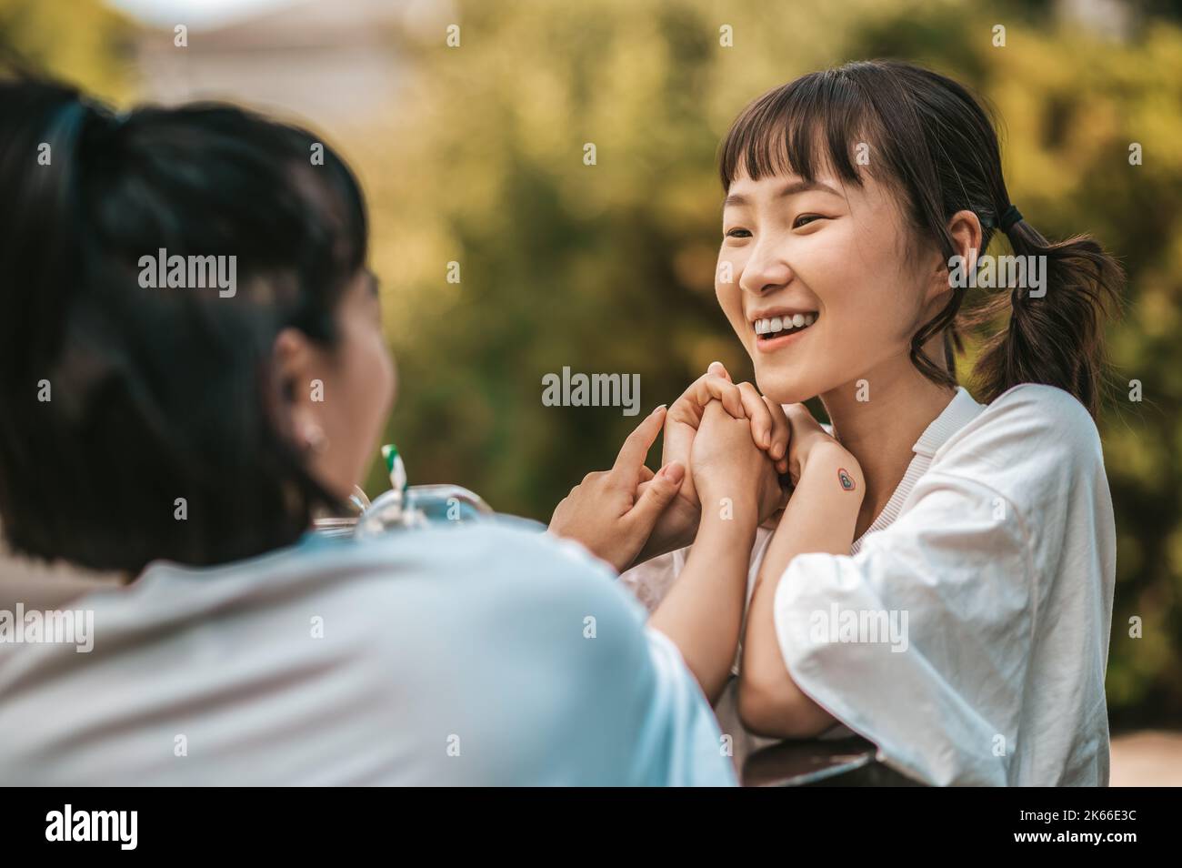 Two asian young girls having good time together and drinking lemonade ...