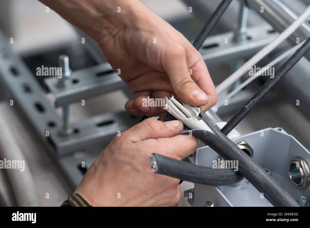 The hands of the electrician removes the electrical insulation of the