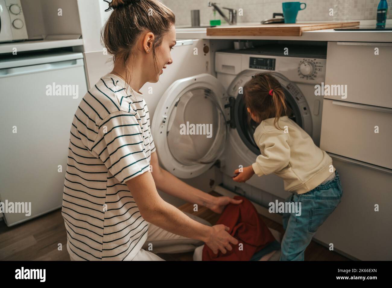 Mom and daughter loading dirty clothes into the washer Stock Photo Alamy