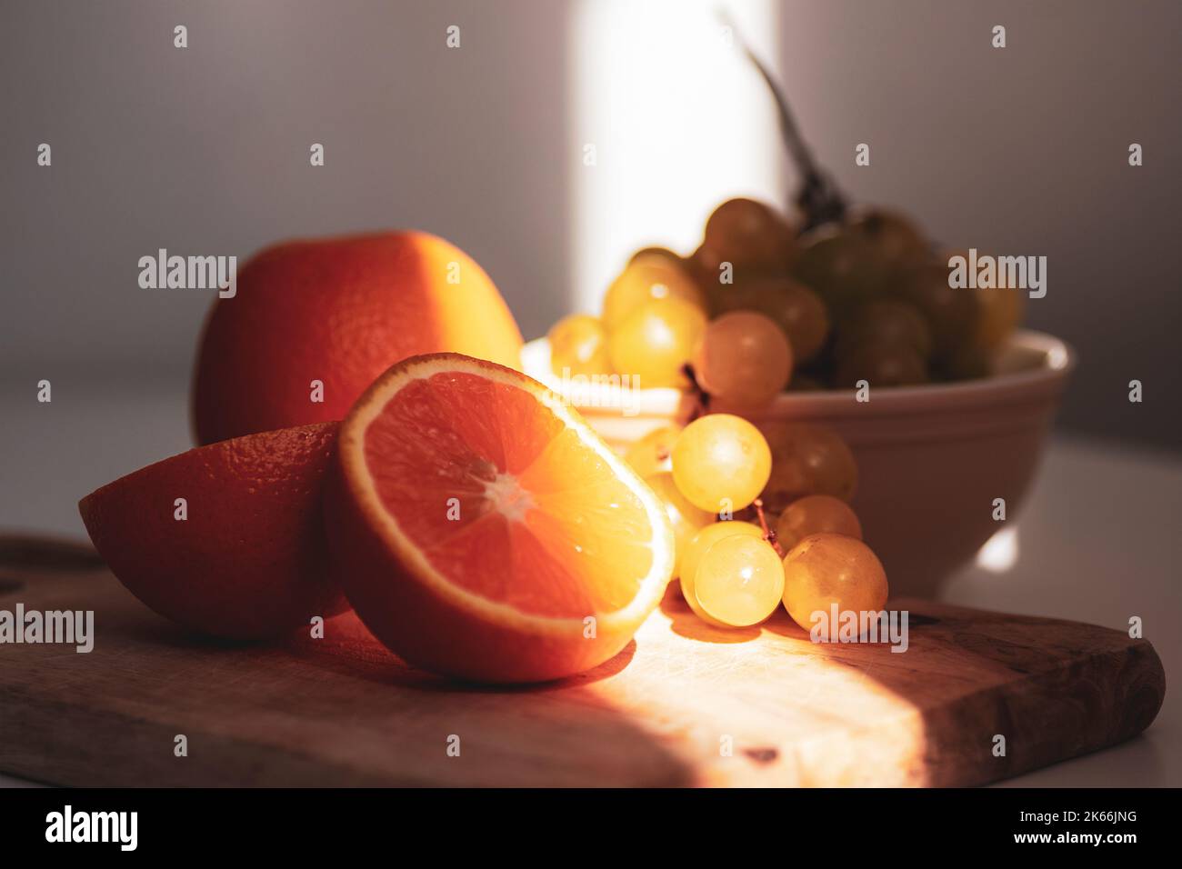 Oranges and grapes on cutting board in sunlight. Still life. Closeup Stock Photo