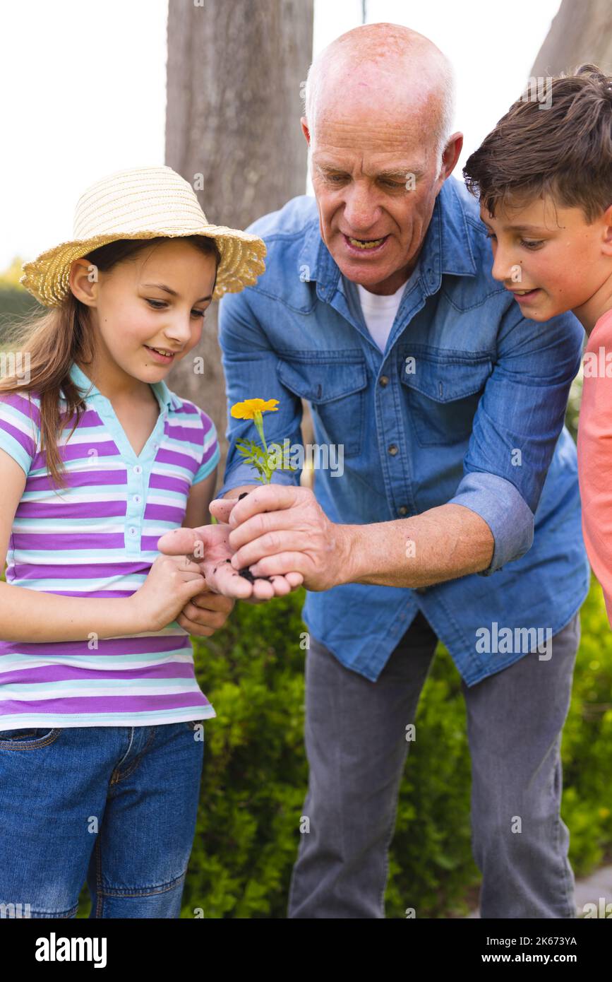 Vertical picture of caucasian children and grandfather spending time together in the garden Stock Photo