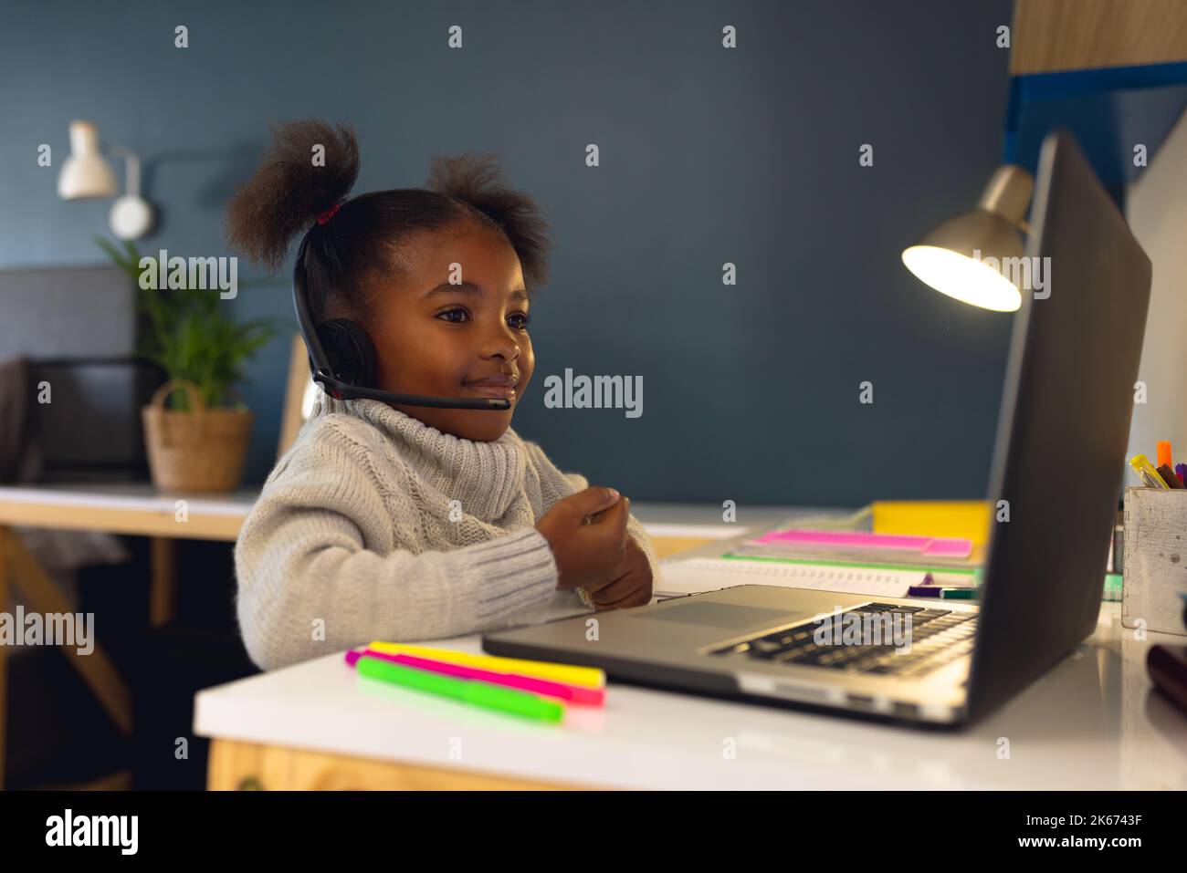 Happy african american girl learning, using laptop and headphone at home Stock Photo