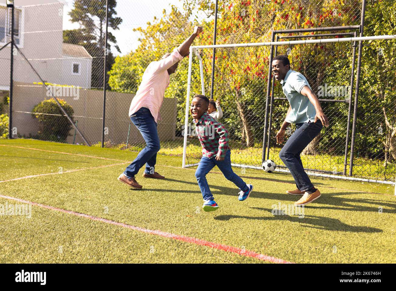 Happy african american family spending time together and playing football outside Stock Photo