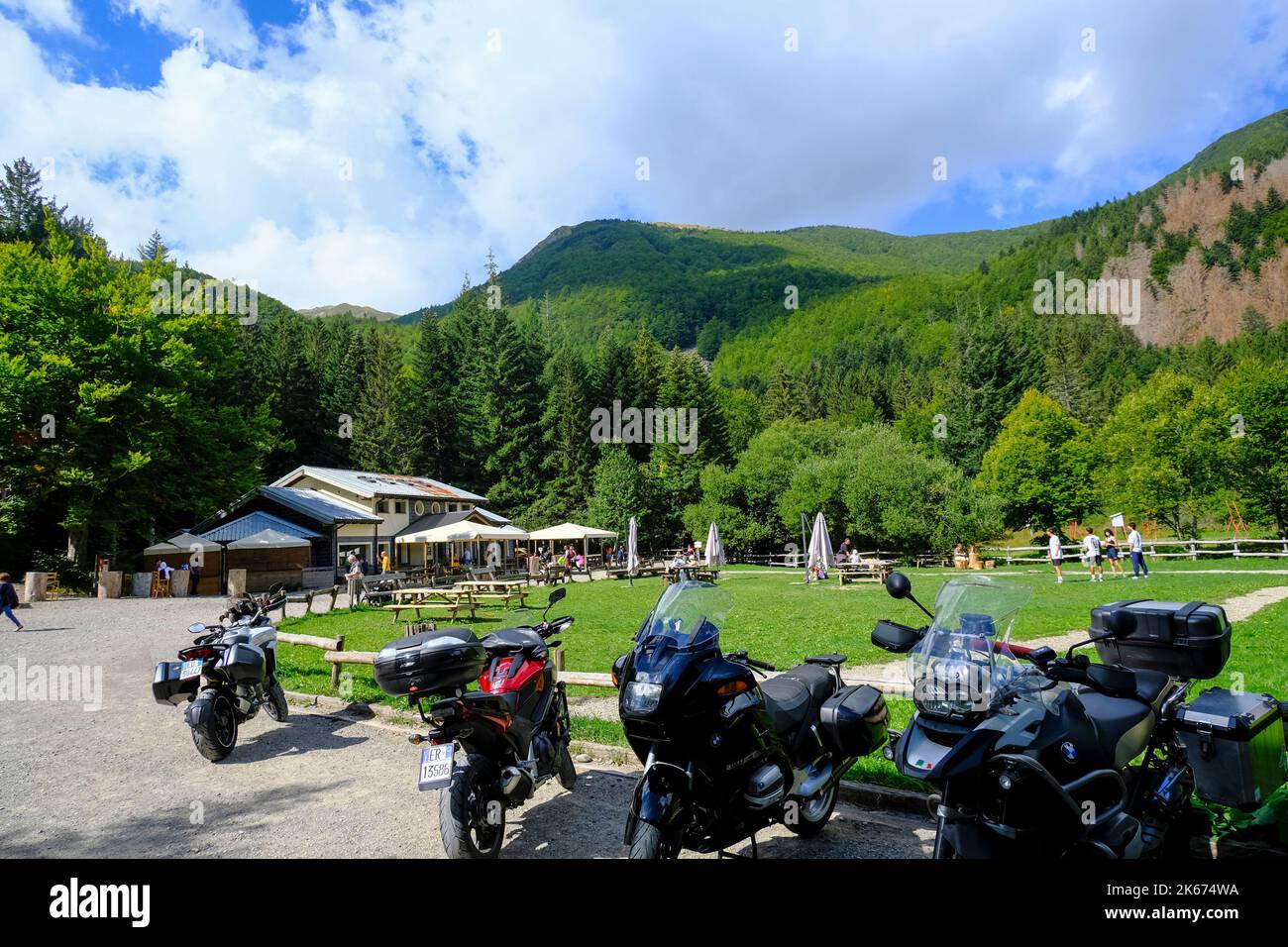 Shelter in the mountains with tourists across parked motorcycles. National park Appennino Tosco-Emiliano, Lagdei, Emilia-Romagna Stock Photo