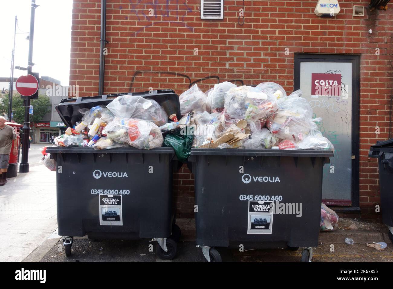 Overflowing unsorted waste bins at Costa containing many metal and carboard items which should have been recycled Romford Essex UK Stock Photo