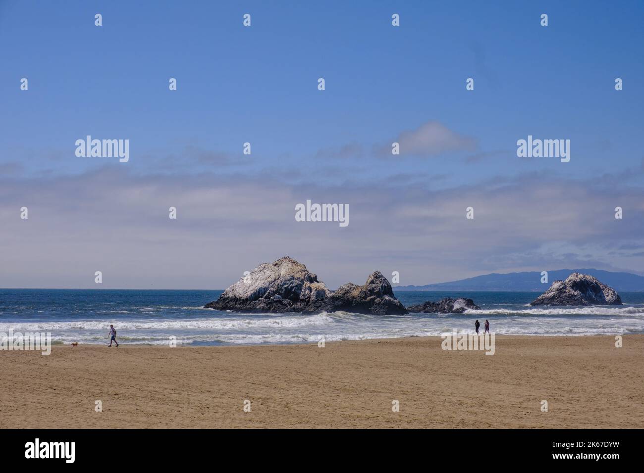 Three people walk along Ocean Beach, at Lands End, San Francisco, California, USA Stock Photo