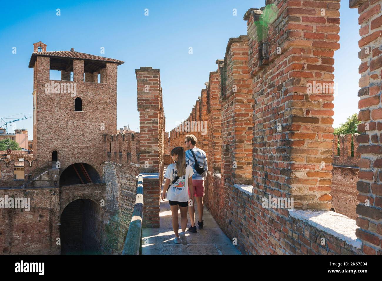 Young people travel, rear view in summer of a tourist couple exploring the fortress walls of the Castelvecchio in Verona, Italy Stock Photo