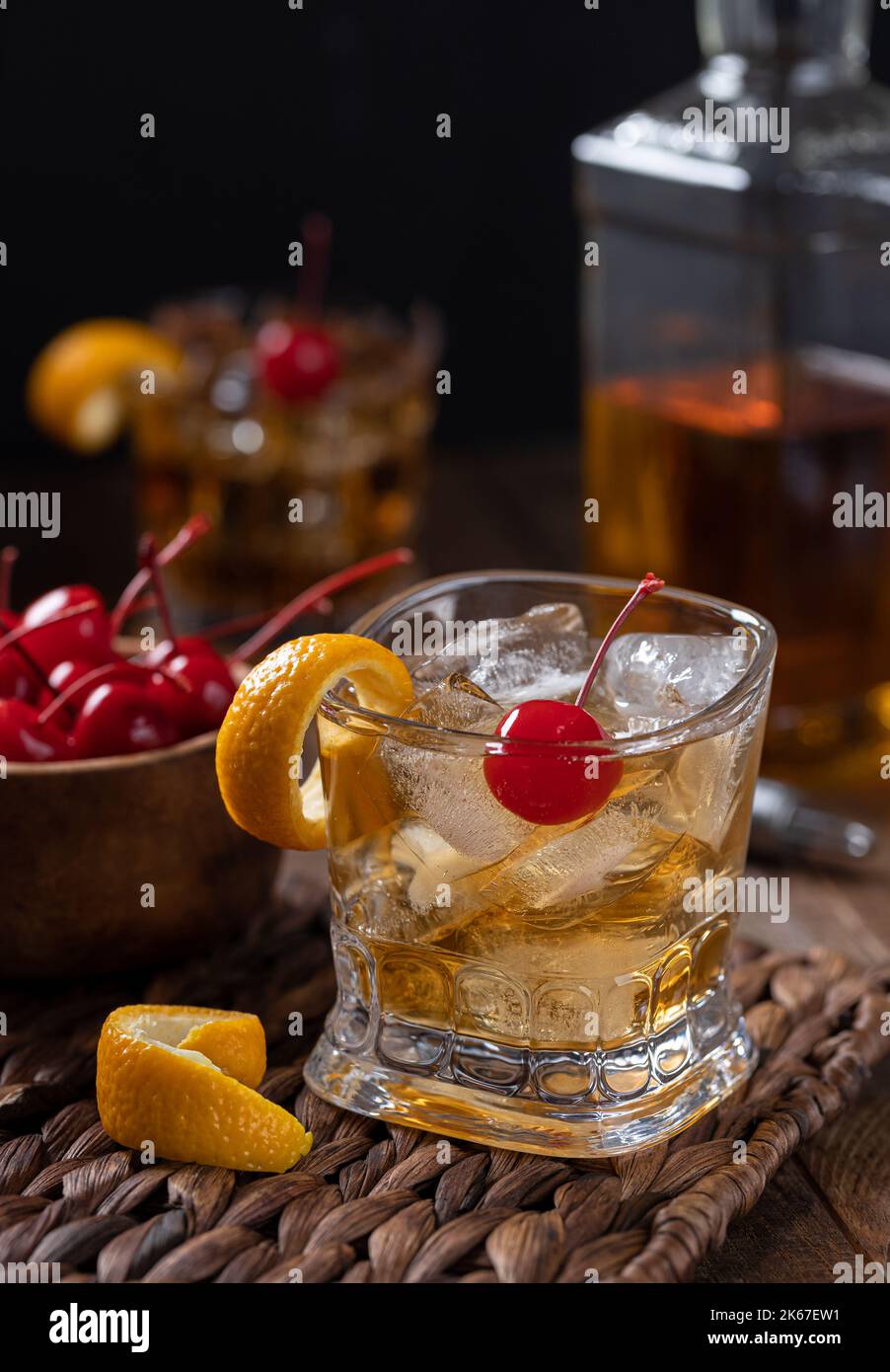 Old fashioned cocktail with orange peel and cherry on a wooden table