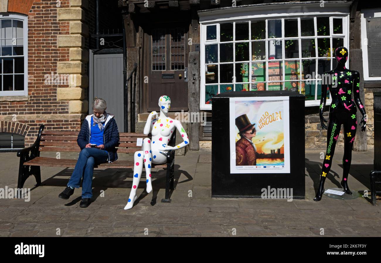 Woman sat on a bench, with a mannequin artwork Stock Photo