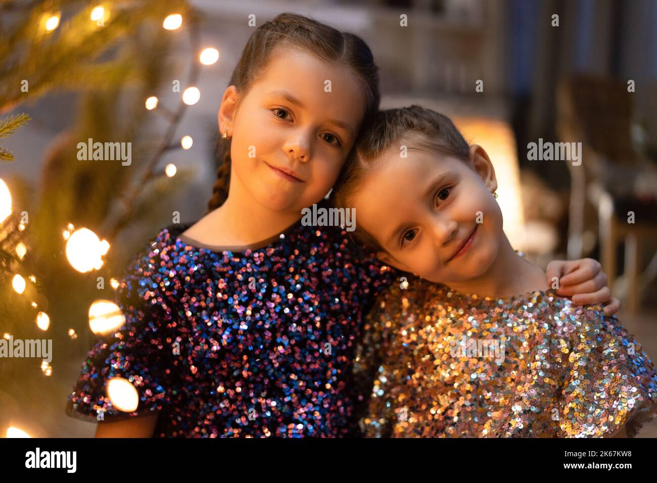 Two cute little girls under Christmas tree. Children under Christmas tree with gift boxes. New Year's decorations. Sisters Stock Photo