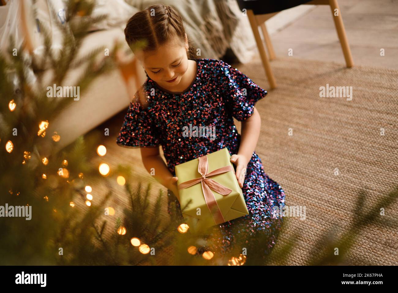 Happy holidays. Little child opening present near Christmas tree. The girl laughing and enjoying the gift Stock Photo