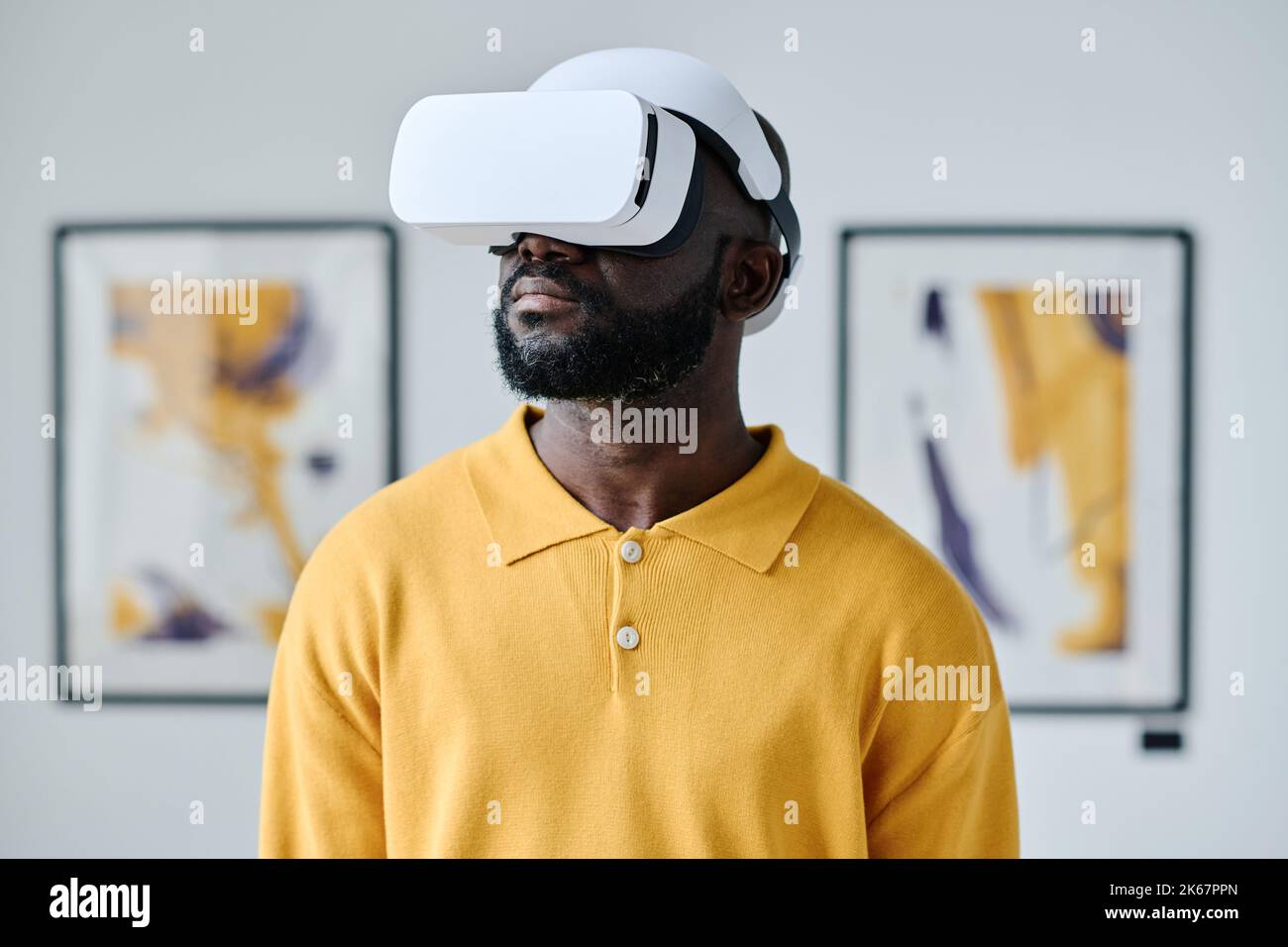 African young man in virtual reality glasses visiting gallery of modern art Stock Photo