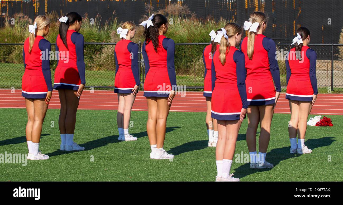 Rear view of high school cheeleaders staning still ready to practice a
