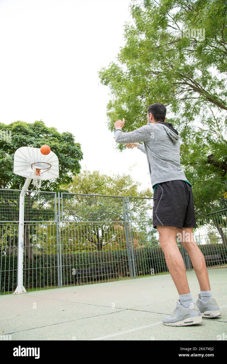 Vertical photo of a basketball player training alone in an outdoor