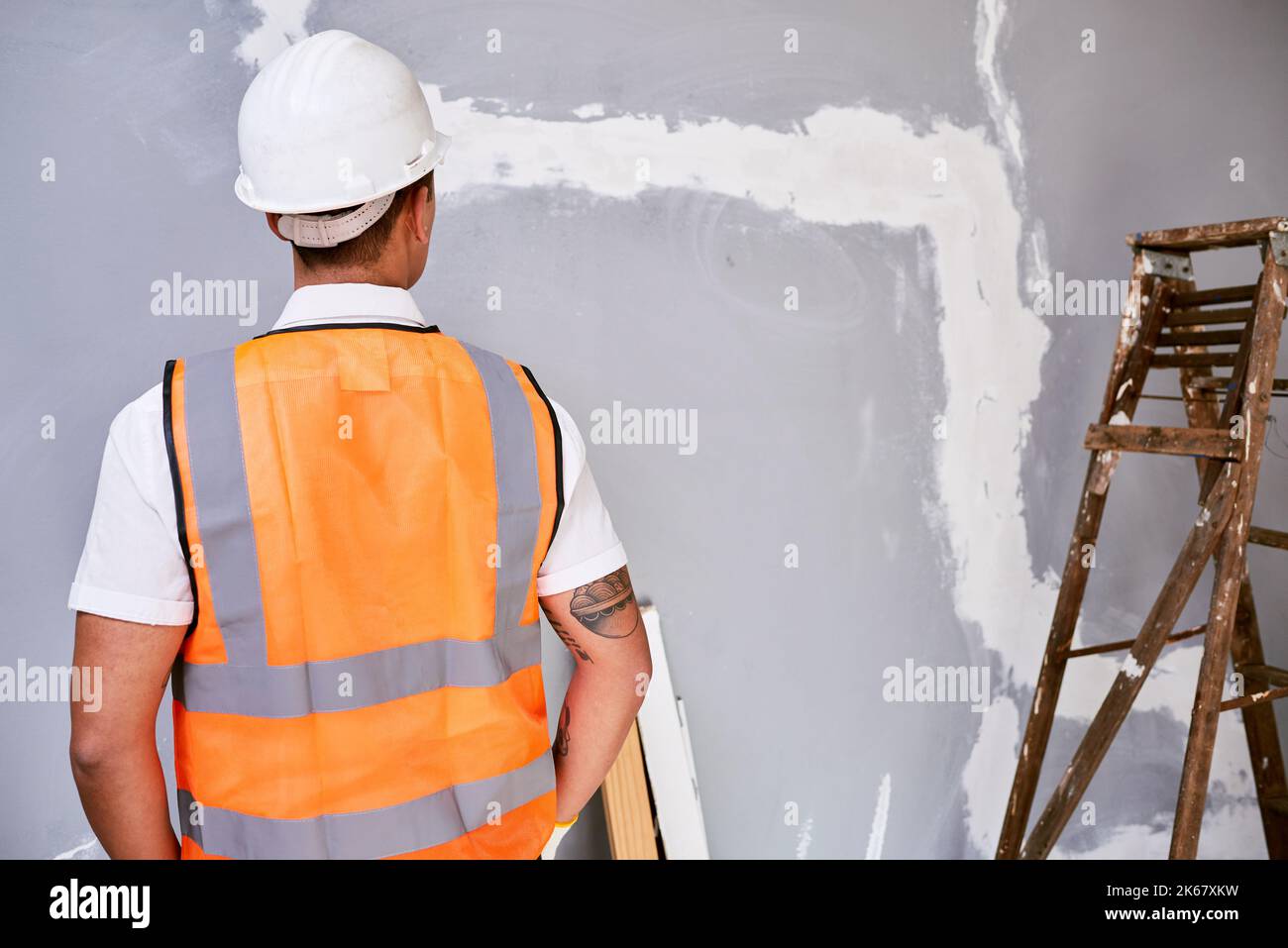 The back of a construction worker in uniform as he faces work in progress Stock Photo