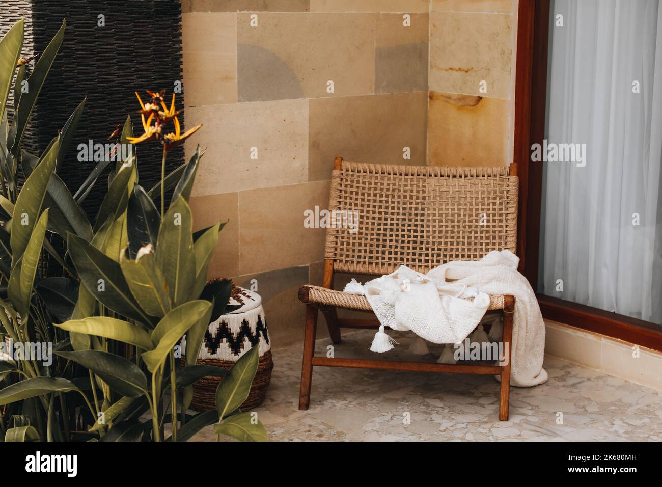 Wicker chair with a white blanket on the summer veranda. Balinese style home decor Stock Photo