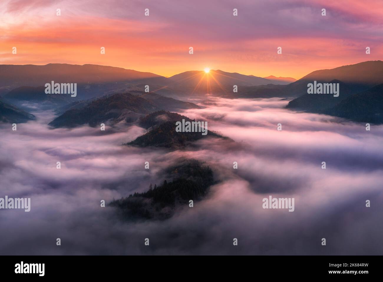 Aerial view of mountains in low clouds at sunrise in autumn Stock Photo