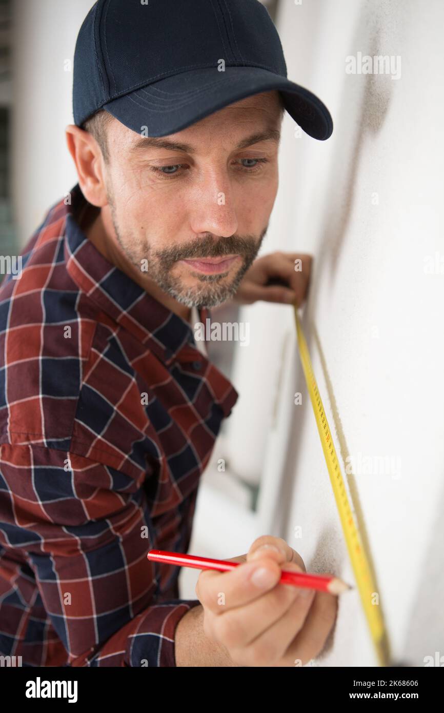 man measures a wall with a ruler Stock Photo