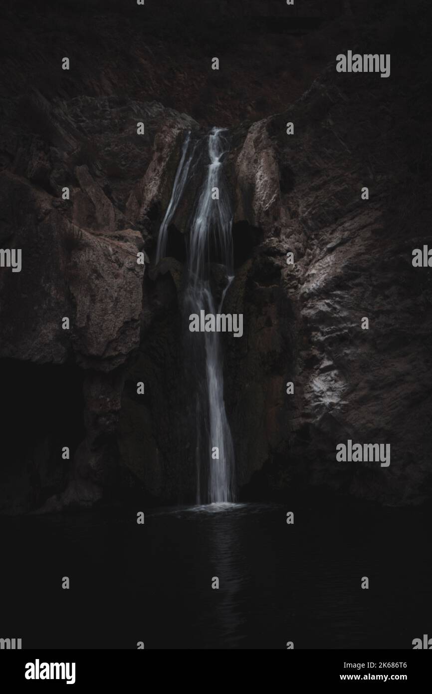 A beautiful scenery of a waterfall flowing down the rocks into the lake ...
