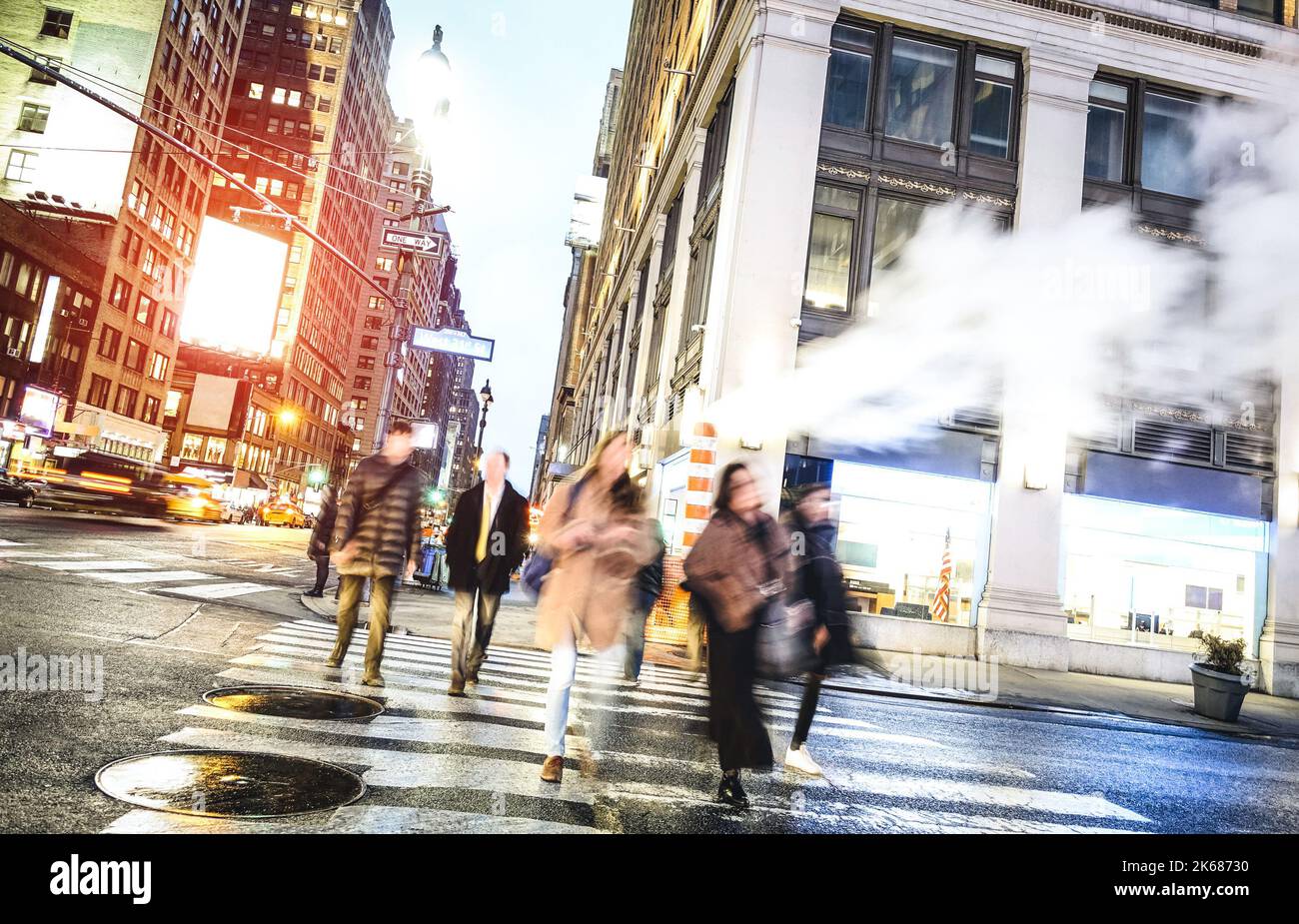 People walking on zebra crossing on West 31th st in Manhattan - Crowded streets of New York City during rush hour in urban business area - Warm desaur Stock Photo