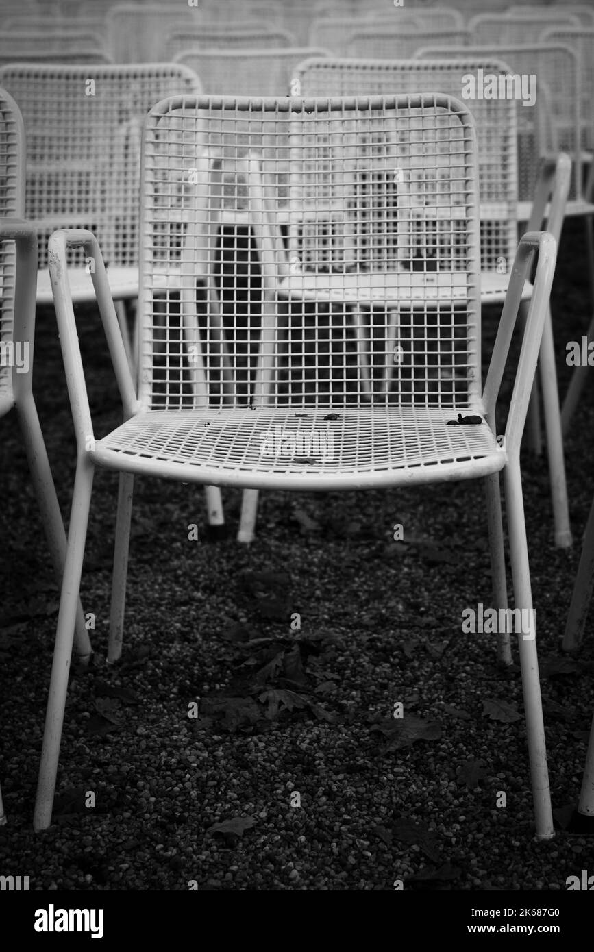 Rows of white metal garden chairs in front of an outdoor stage. Stock Photo