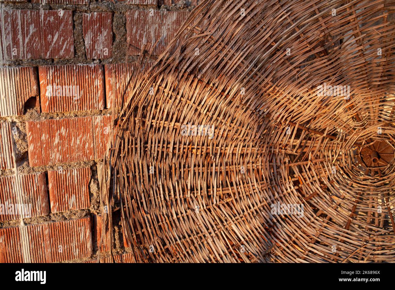 straw beach umbrella hat and red brick wall on a summer day, straw beach umbrella. end of tourist season. Stock Photo