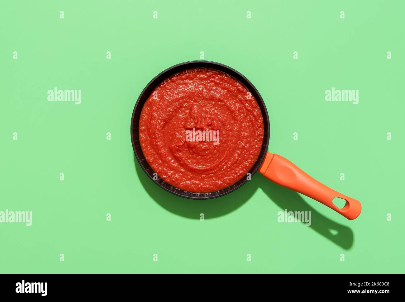 Above view with homemade tomato sauce in a pan on a green table. Traditional italian tomato sauce with garlic and basil for pasta or pizza, Stock Photo