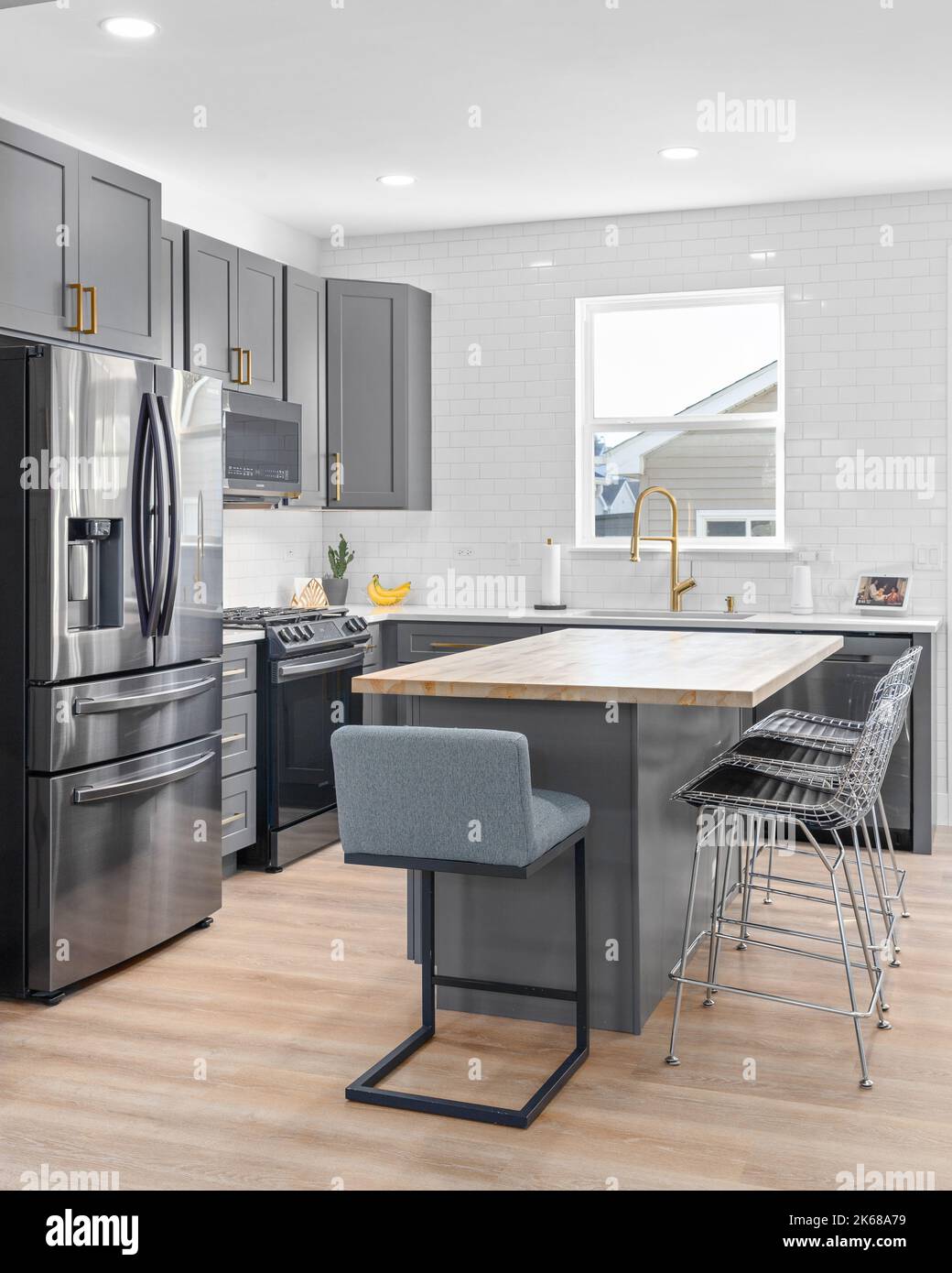 A kitchen with dark grey cabinets, large island with a wood countertop ...