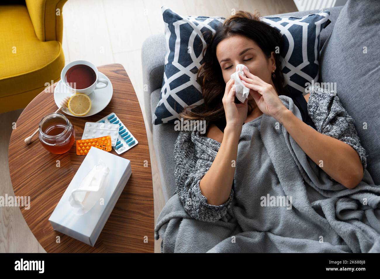 Sick woman blows her nose into a handkerchief, lying on bed Stock Photo