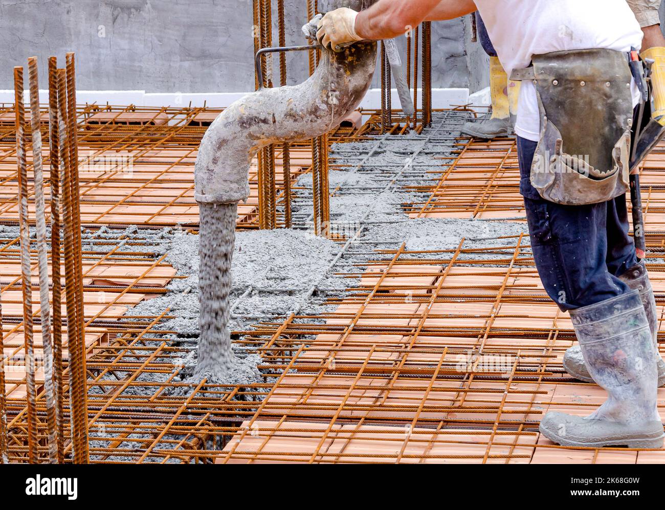 Building construction worker pouring cement or concrete with pump tube