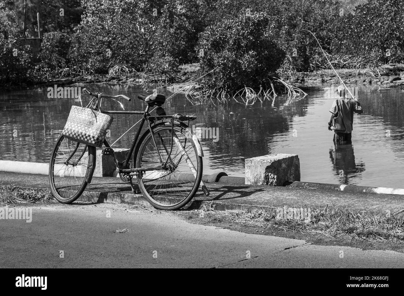 Parked bicycle with a man river fishing near Mahebourg, Mauritius Stock Photo